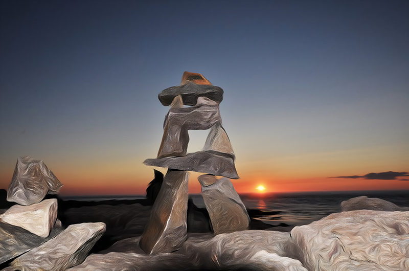 An inukshuk on a shoreline in front of a sunset